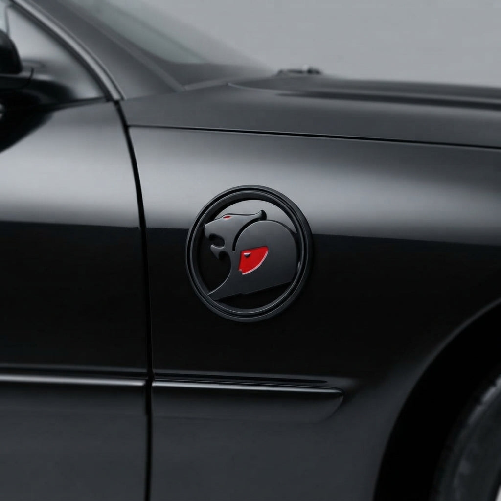 Black round 3D metal badge with red accent on the front fender of a black car, near the door seam