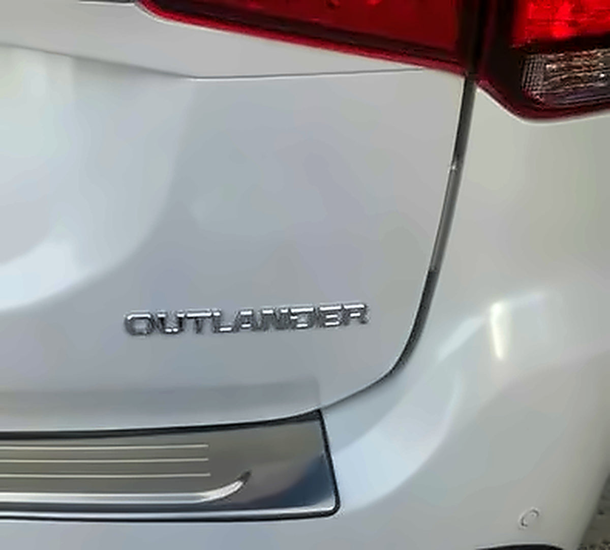 Mitsubishi Outlander chrome rear emblem lettering on white vehicle tailgate